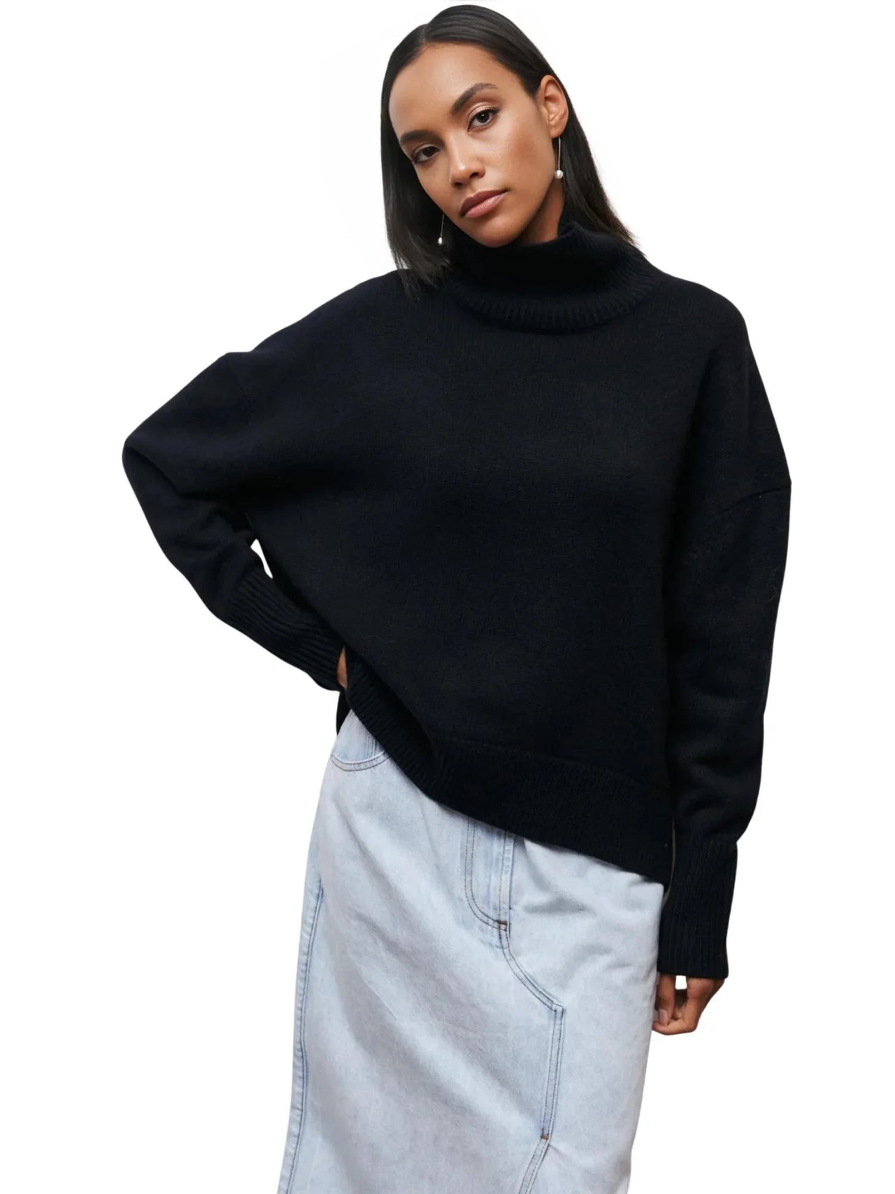 Woman wearing a black turtleneck sweater and light blue jeans on a white background