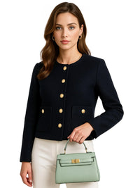 Thumbnail for Woman wearing a black jacket with gold buttons, holding a green handbag on a white background
