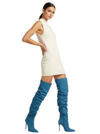 Thumbnail for Woman wearing a white dress and blue over-the-knee-high suede boots on a white background