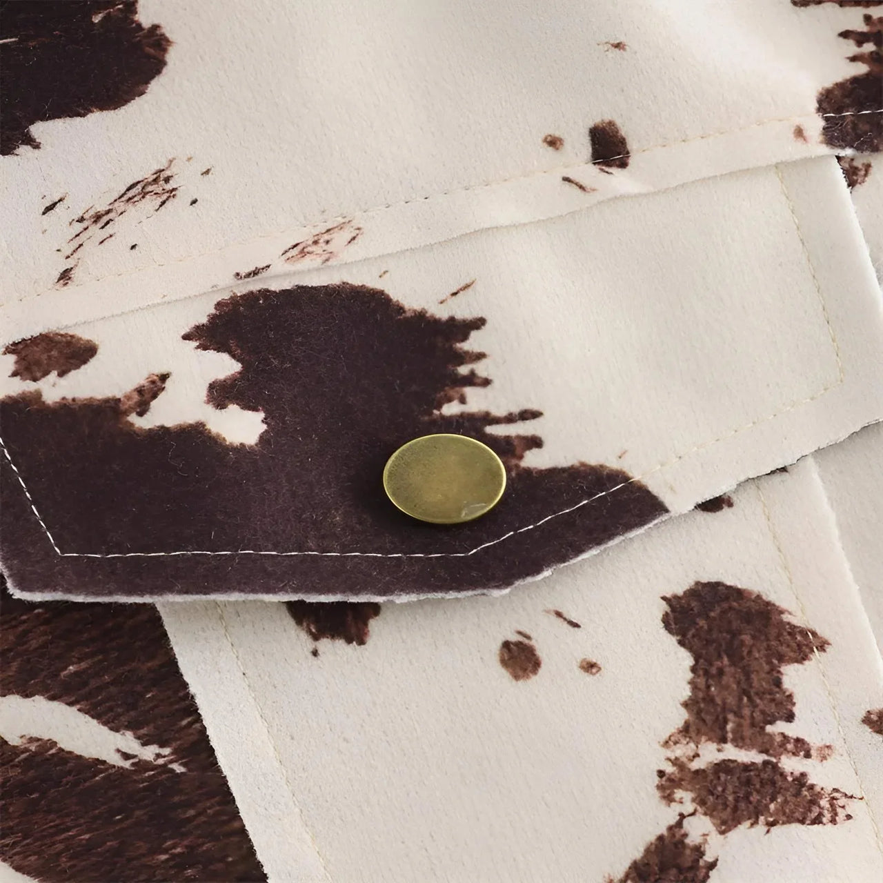 Close-up of a brown and white patterned fabric with a gold button on top.