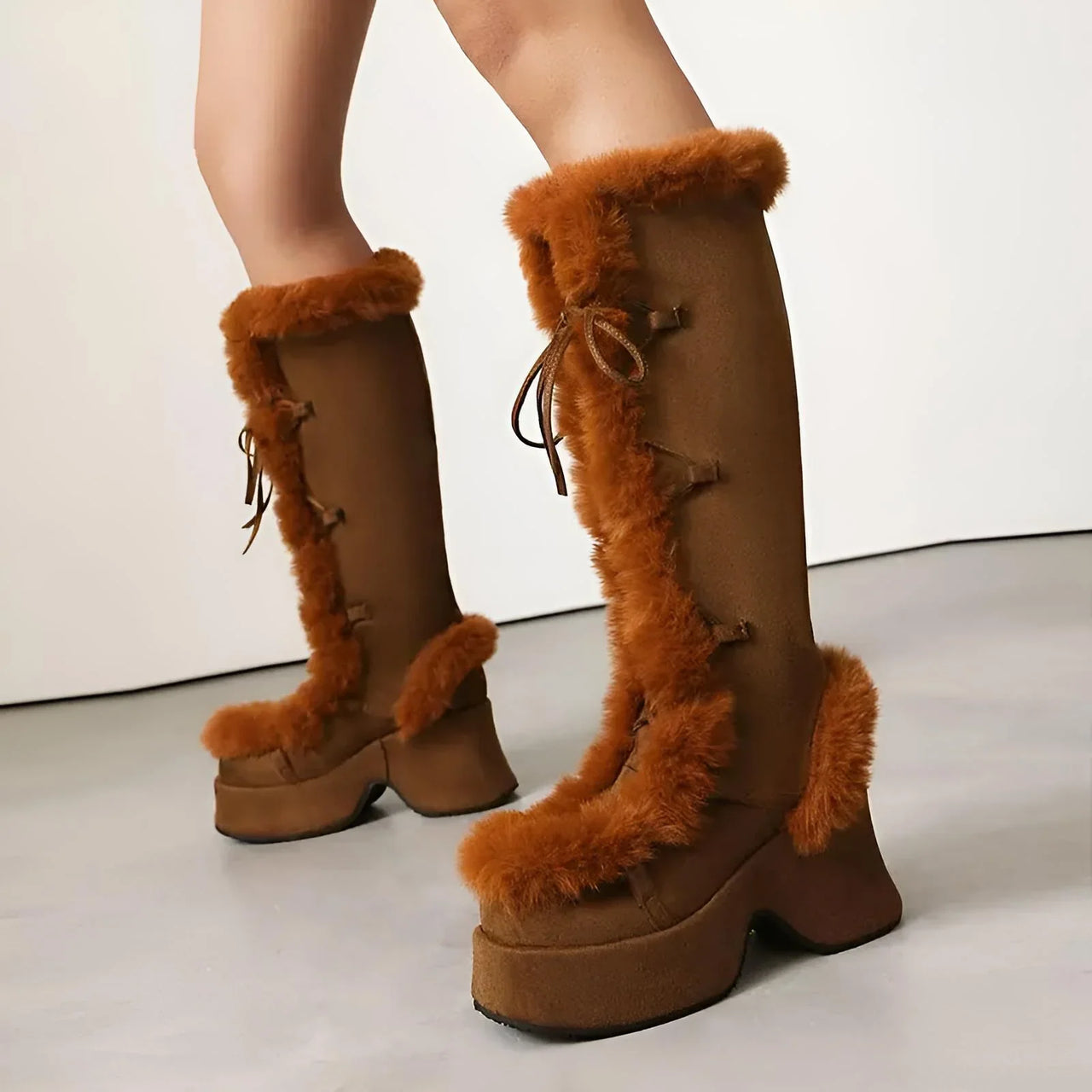 Brown knee-high platform boots with fur trim on a neutral background