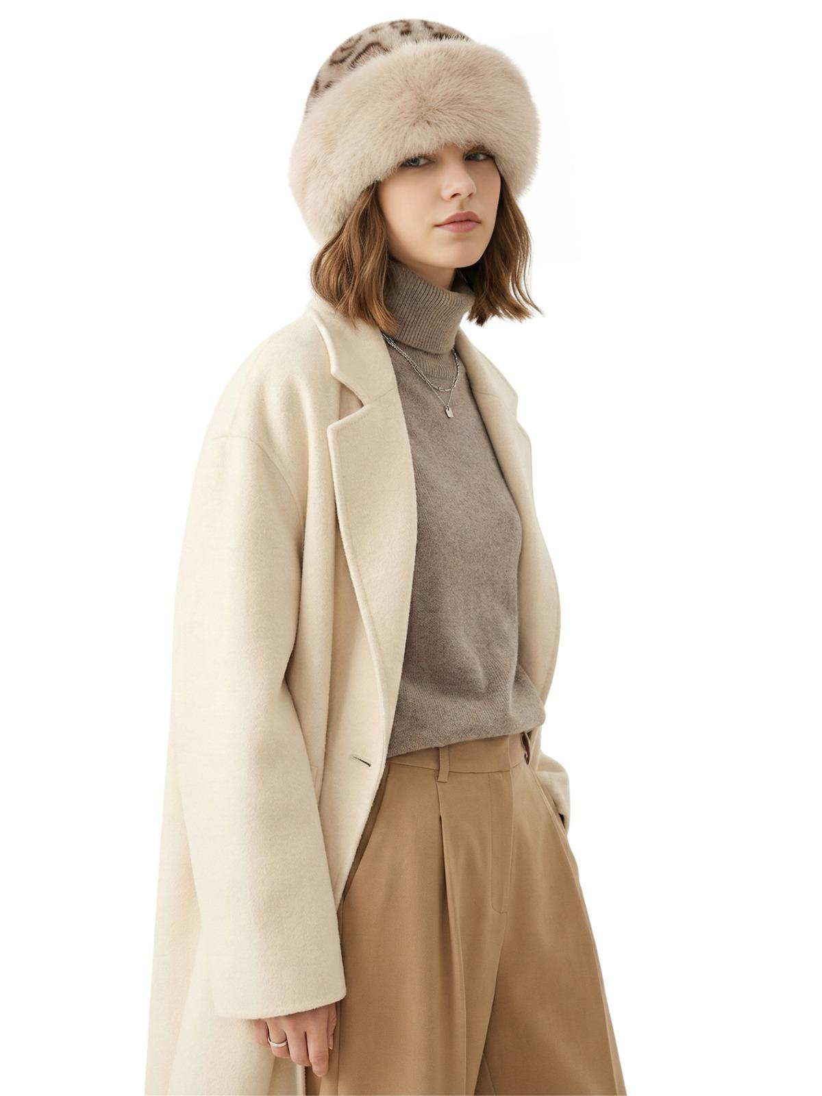 Woman wearing a cream coat, brown sweater, beige pants, and a beige leopard print faux fur hat on a white background