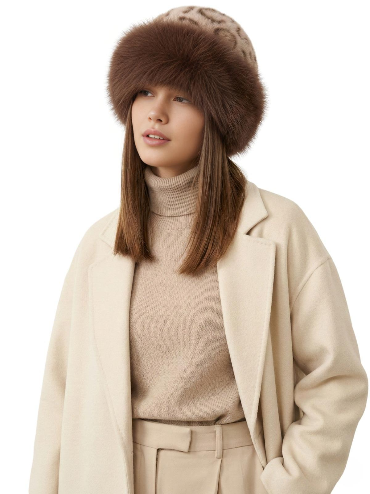 Woman wearing a beige-brown leopard print faux fur hat, beige coat, and sweater on a white background