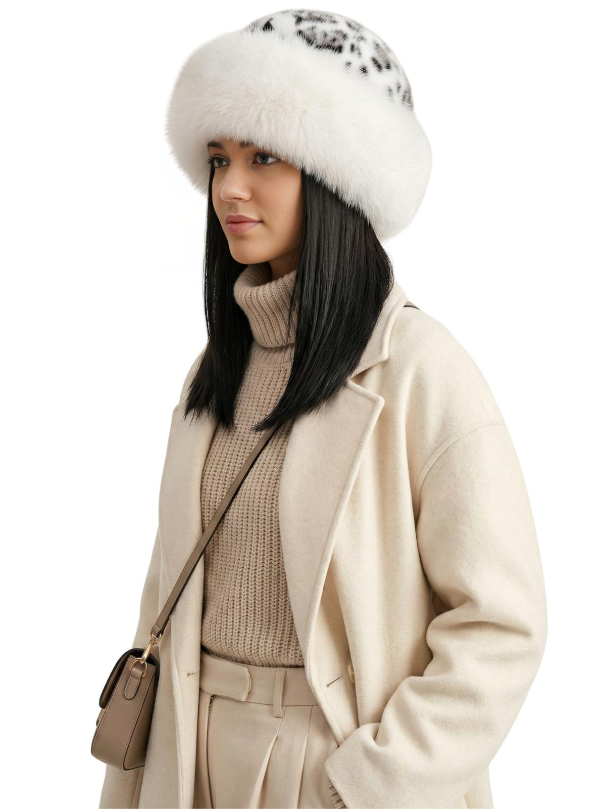 Woman wearing a white-black leopard print faux fur hat, beige coat, and sweater on a white background