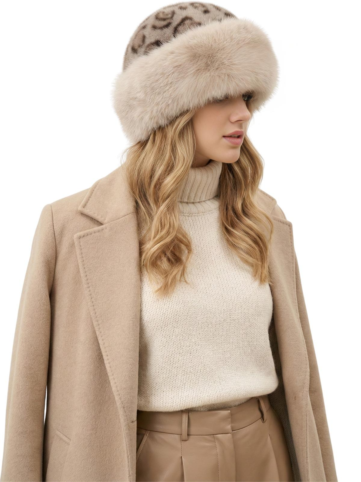 Woman wearing a beige leopard print faux fur hat, beige coat, and white sweater on a white background