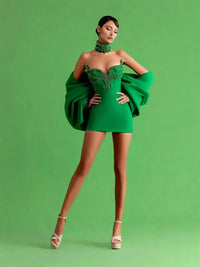Thumbnail for Model wearing a green mini dress with embellishments on a green background