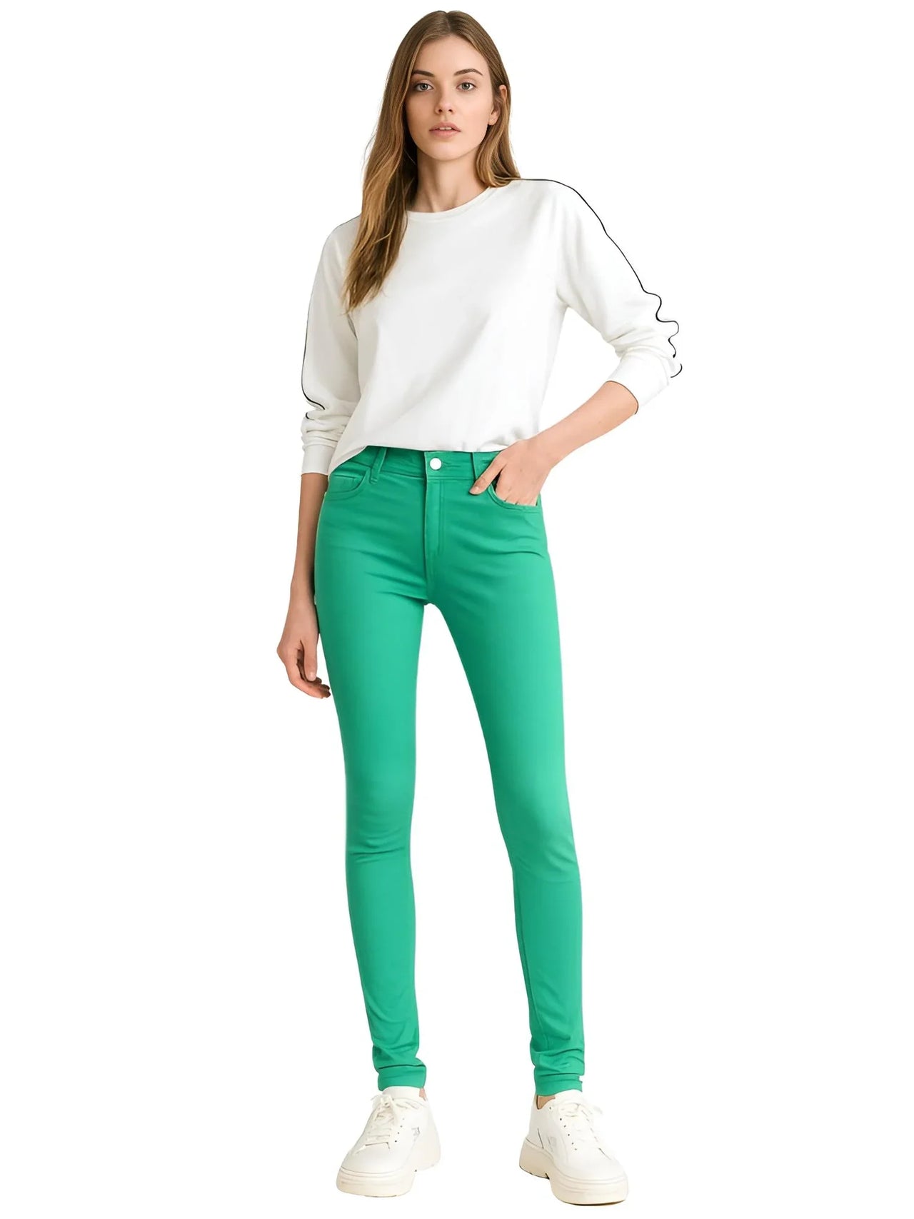 Woman wearing green skinny jeans and a white top on a white background