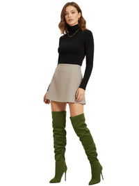 Thumbnail for Woman wearing a black turtleneck, beige skirt, and green knee-high suede boots on a white background