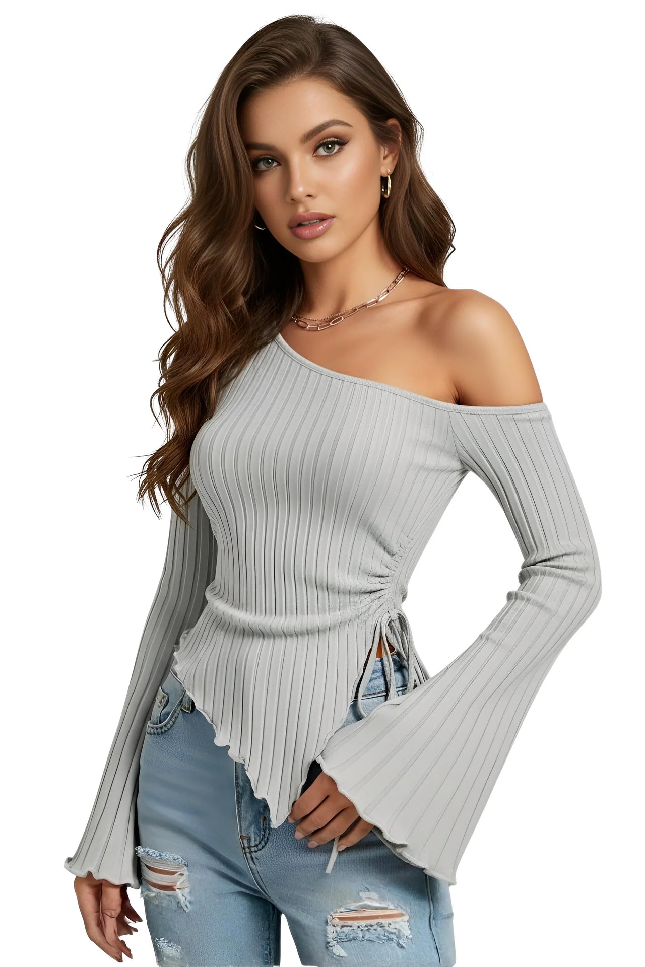 Woman wearing an asymmetrical gray ribbed off-shoulder sweater with long flared sleeves and ripped jeans on a white background