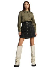 Thumbnail for Woman wearing a green shirt and black skirt with white knee-high boots on a white background
