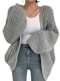 Thumbnail for Person wearing a gray knitted cardigan over a white top and blue jeans on a white background