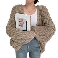 Thumbnail for Person wearing a chunky knit sweater holding a photo album with a white cover.