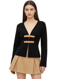 Thumbnail for Woman wearing a black sweater jacket with brown buckles and a beige skirt on a white background