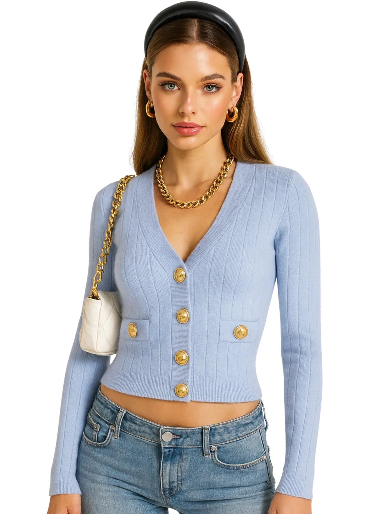 Woman wearing a light blue cardigan with gold buttons, holding a white handbag.
