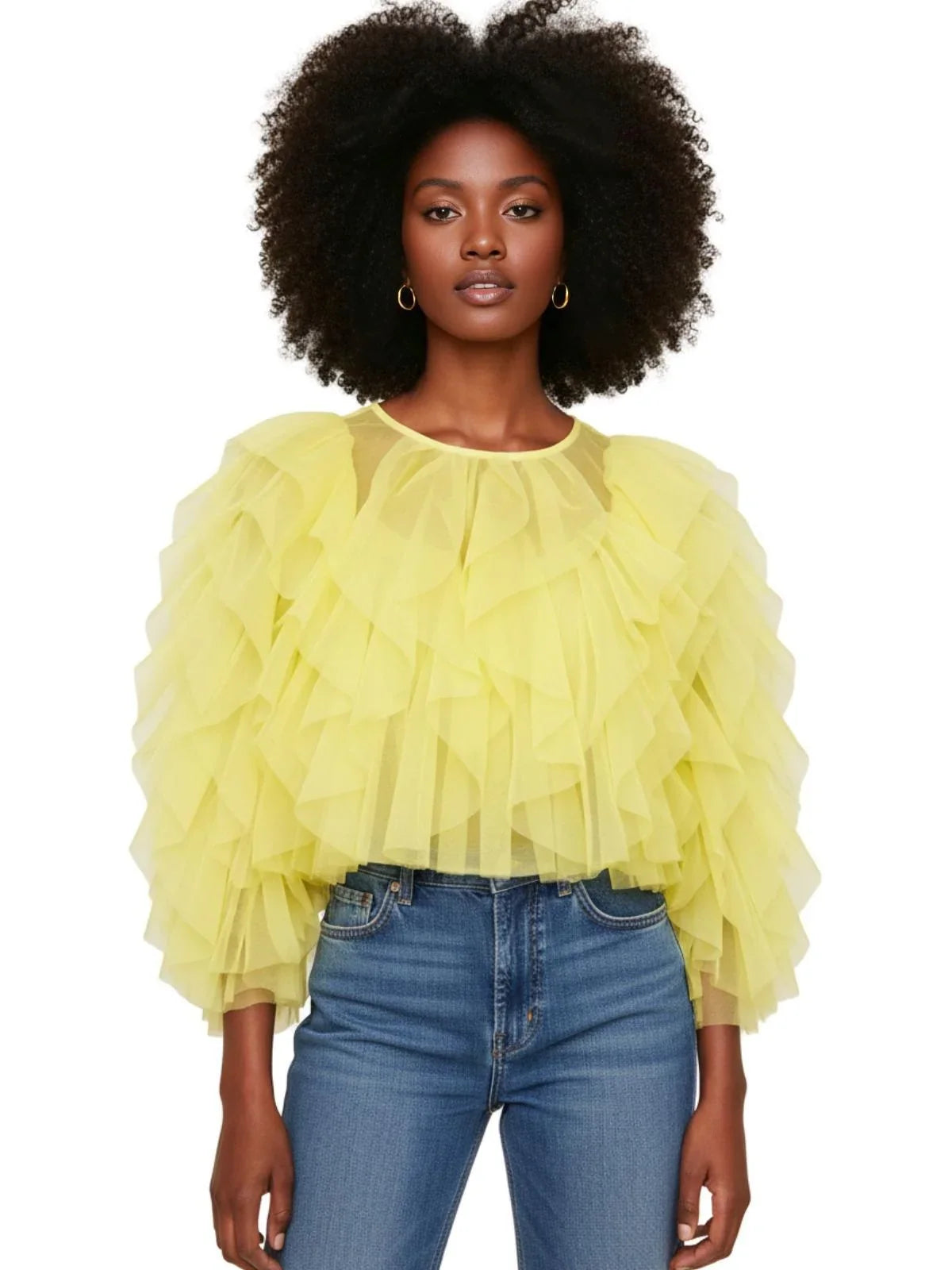 Woman wearing a yellow ruffled blouse and blue jeans on a white background