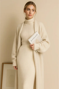Thumbnail for Woman in a beige knit outfit and a long white fluffy cardigan holding a book against a beige background