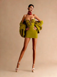 Thumbnail for Woman wearing a green cocktail dress with a large green jacket against a beige background