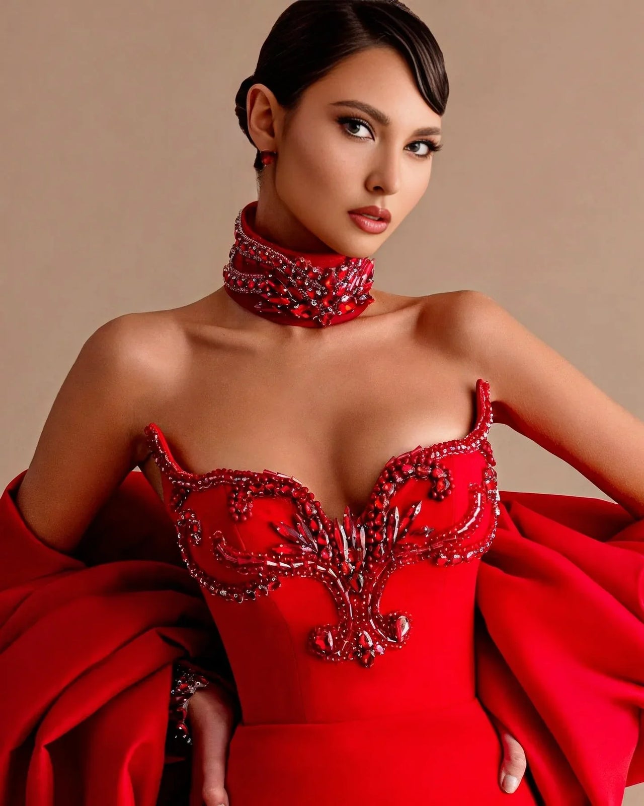 Woman wearing a red beaded dress with a beige background