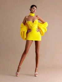 Thumbnail for Woman wearing a bright yellow mini dress with ruffled sleeves against a beige background