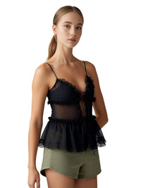 Thumbnail for Woman wearing a black top with sheer details and green shorts on a white background