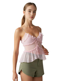 Thumbnail for Woman wearing a pink ruffled top and green shorts on a white background