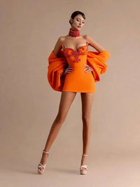 Thumbnail for Woman wearing an orange mini dress with a textured texture on a beige background