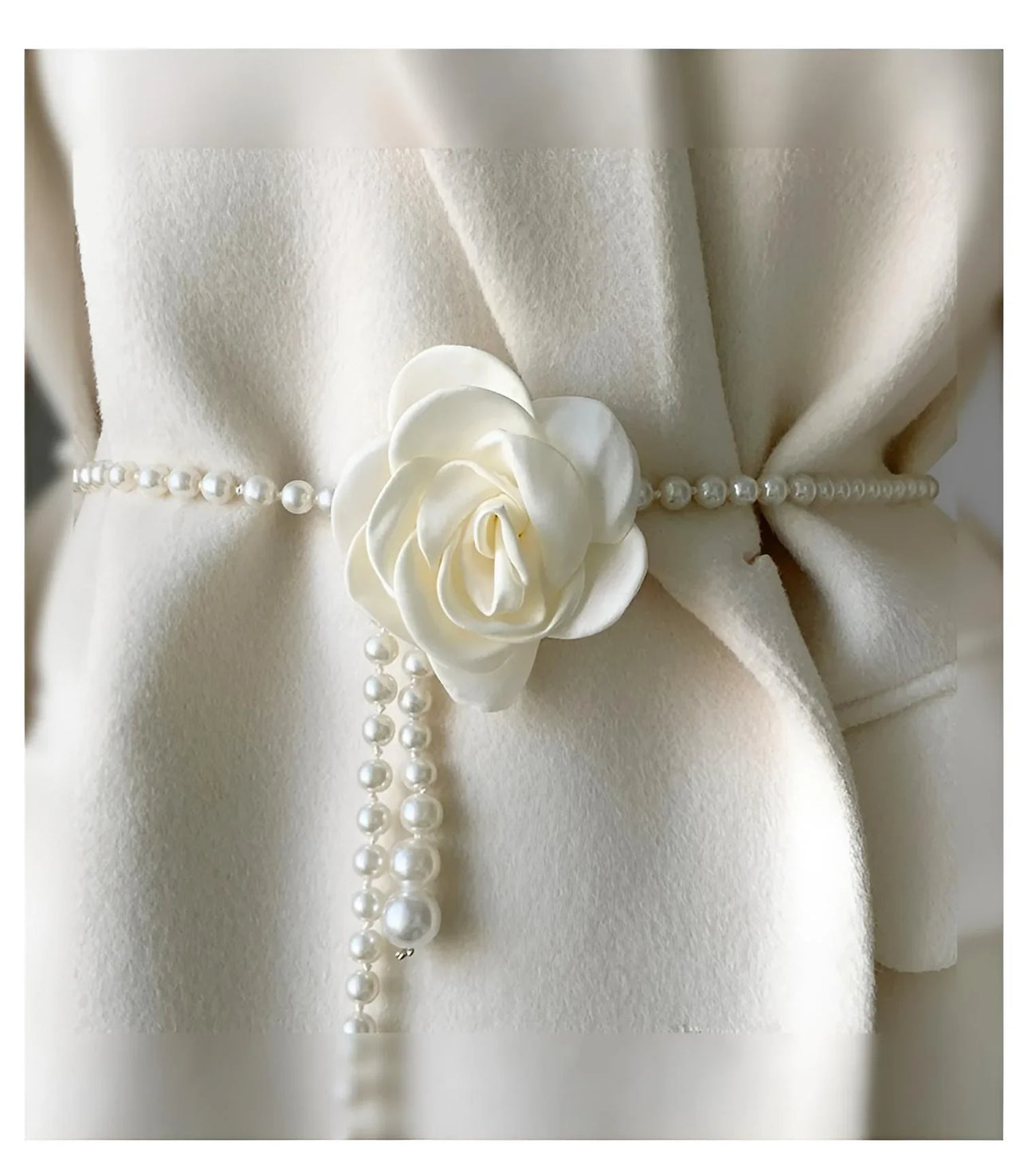 White coat with a decorative pearl belt with a white flower on a white background