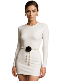 Thumbnail for Woman wearing a white dress with a black flower and pearl belt on a white background