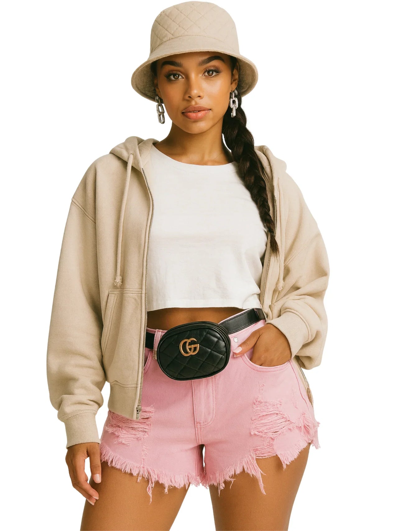 Woman wearing a beige hoodie, white crop top, pink jean shorts, and a beige bucket hat on a white background.