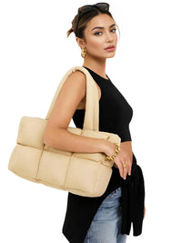 Thumbnail for Woman holding a beige quilted handbag against a white background