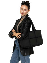 Thumbnail for Woman holding a black puffer bag against a white background