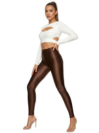 Thumbnail for Woman wearing a white long-sleeve top with cut-out design and brown shiny leggings on a white background