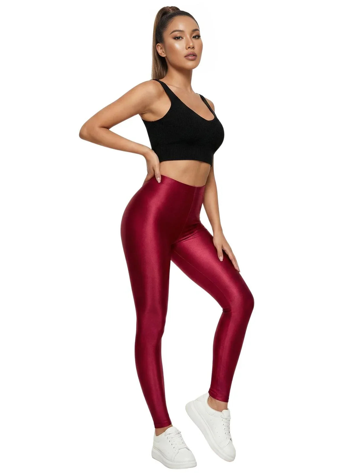 Woman wearing red leggings and a black sports bra on a white background