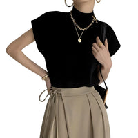 Thumbnail for Woman wearing a black short sleeve sweater and beige high waist pair of pants with gold jewelry on a white background