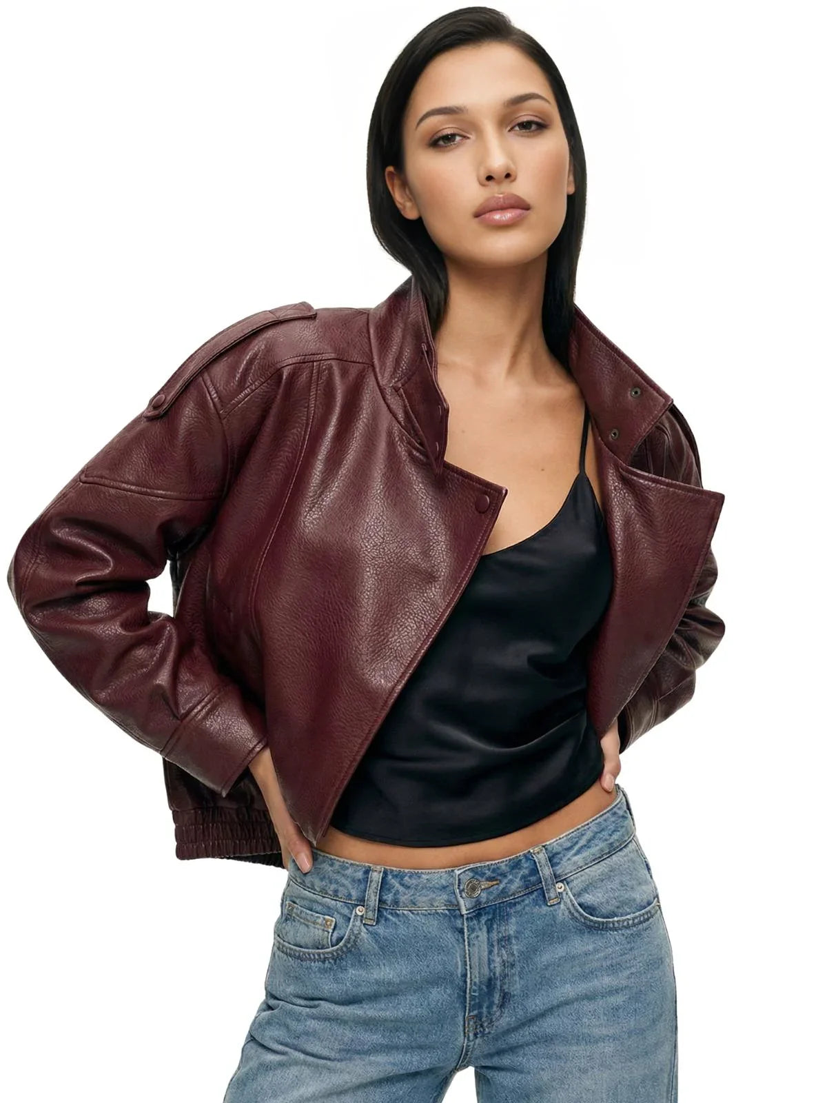 Woman wearing a maroon leather jacket, black top, and blue jeans on a white background