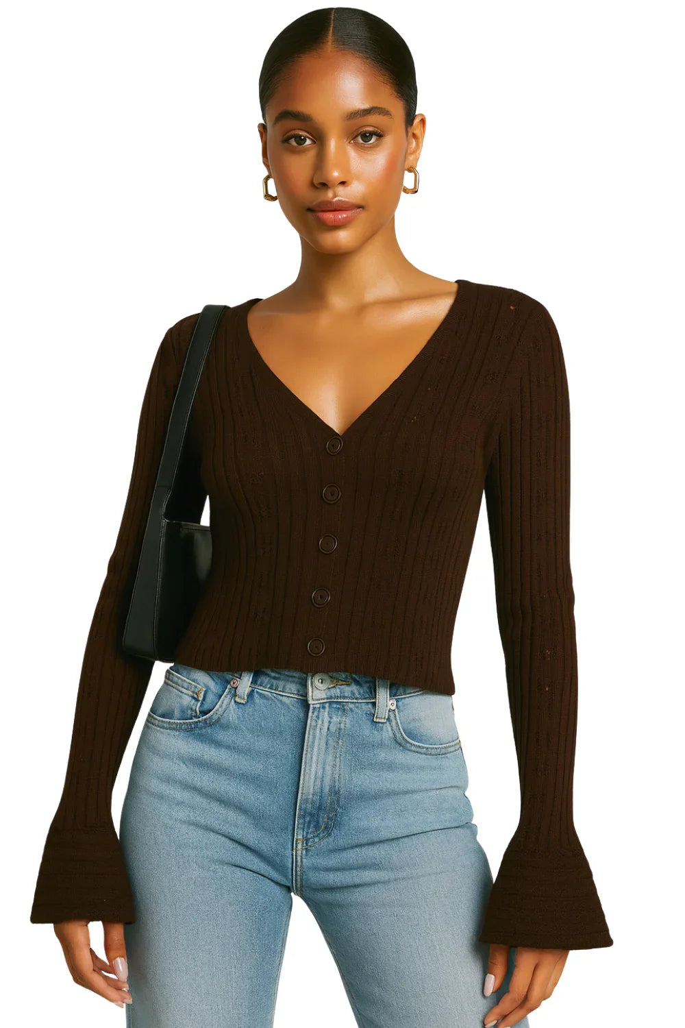 Woman wearing a brown flare sleeve cardigan sweater and blue jeans with a black handbag on a white background