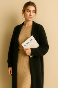 Thumbnail for Woman holding a 'KINOLK' magazine wearing a long black fluffy cardigan and beige dress against a beige background