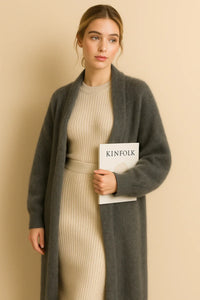 Thumbnail for Woman wearing a long fluffy grey cardigan holding a book titled 'KINFOLK' against a beige background