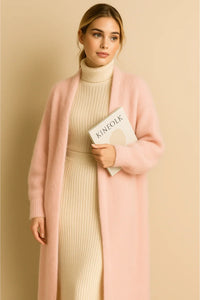 Thumbnail for Woman wearing a long pink fluffy cardigan over a beige dress, holding a book against a beige background